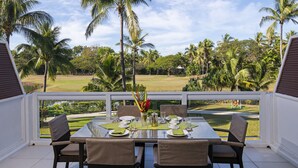 A dining area with a table set for four, overlooking a lush garden with palm trees. - The Terraces Apartments Resort (Nadi)