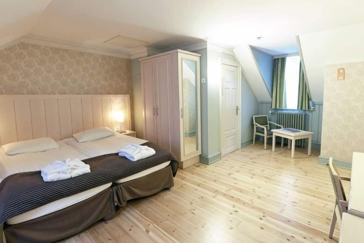 A bedroom with a bed, a wardrobe, a desk, and a chair.