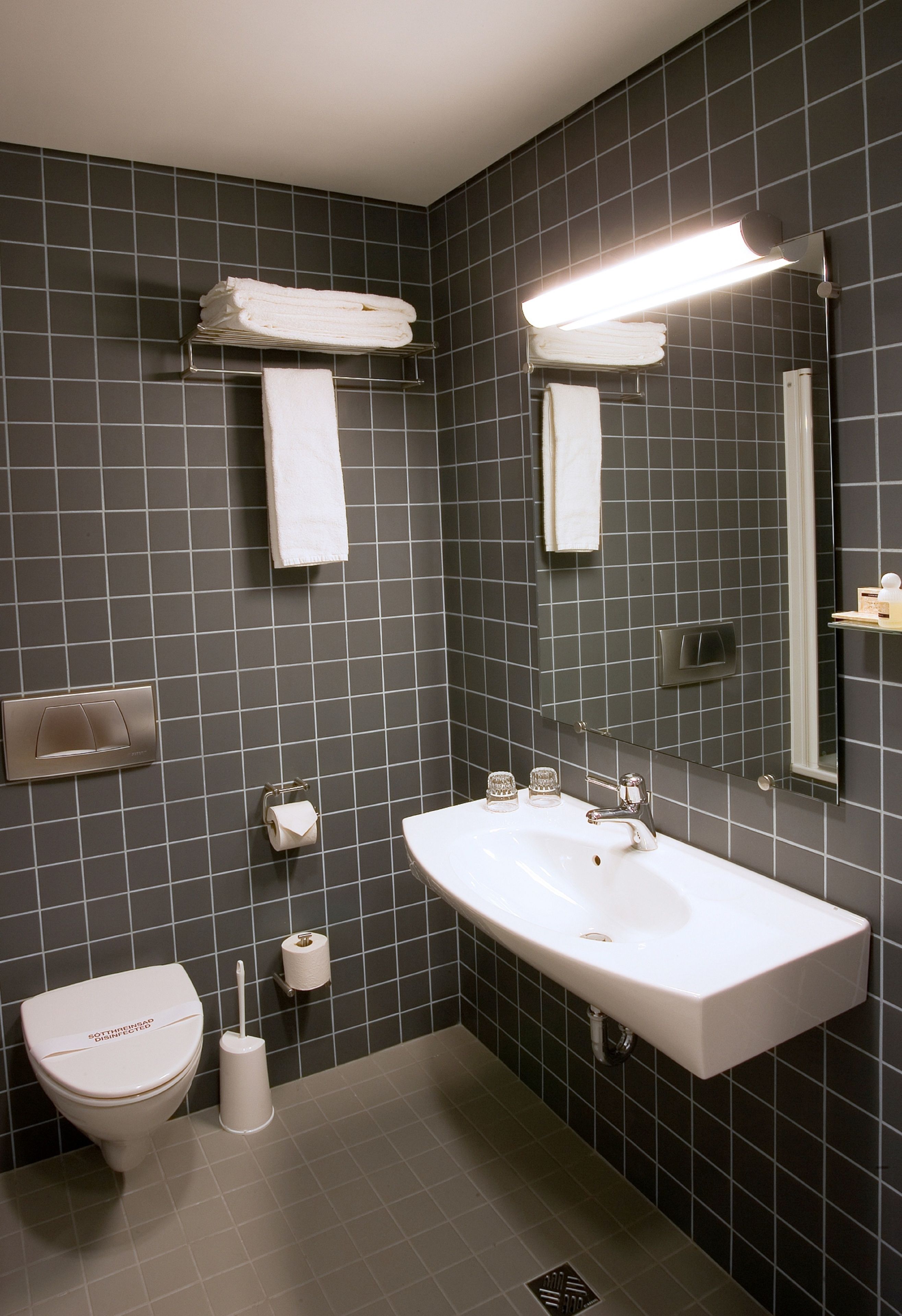 A modern bathroom with a white sink, a toilet, and a mirror.