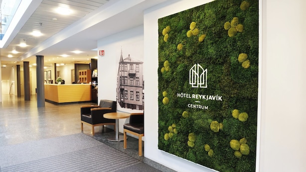 Zona de recepción de un hotel con una pared verde y un mostrador.