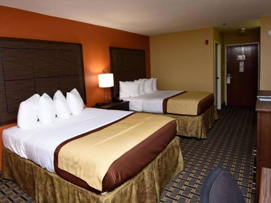 A hotel room with two beds, a desk, and a chair.