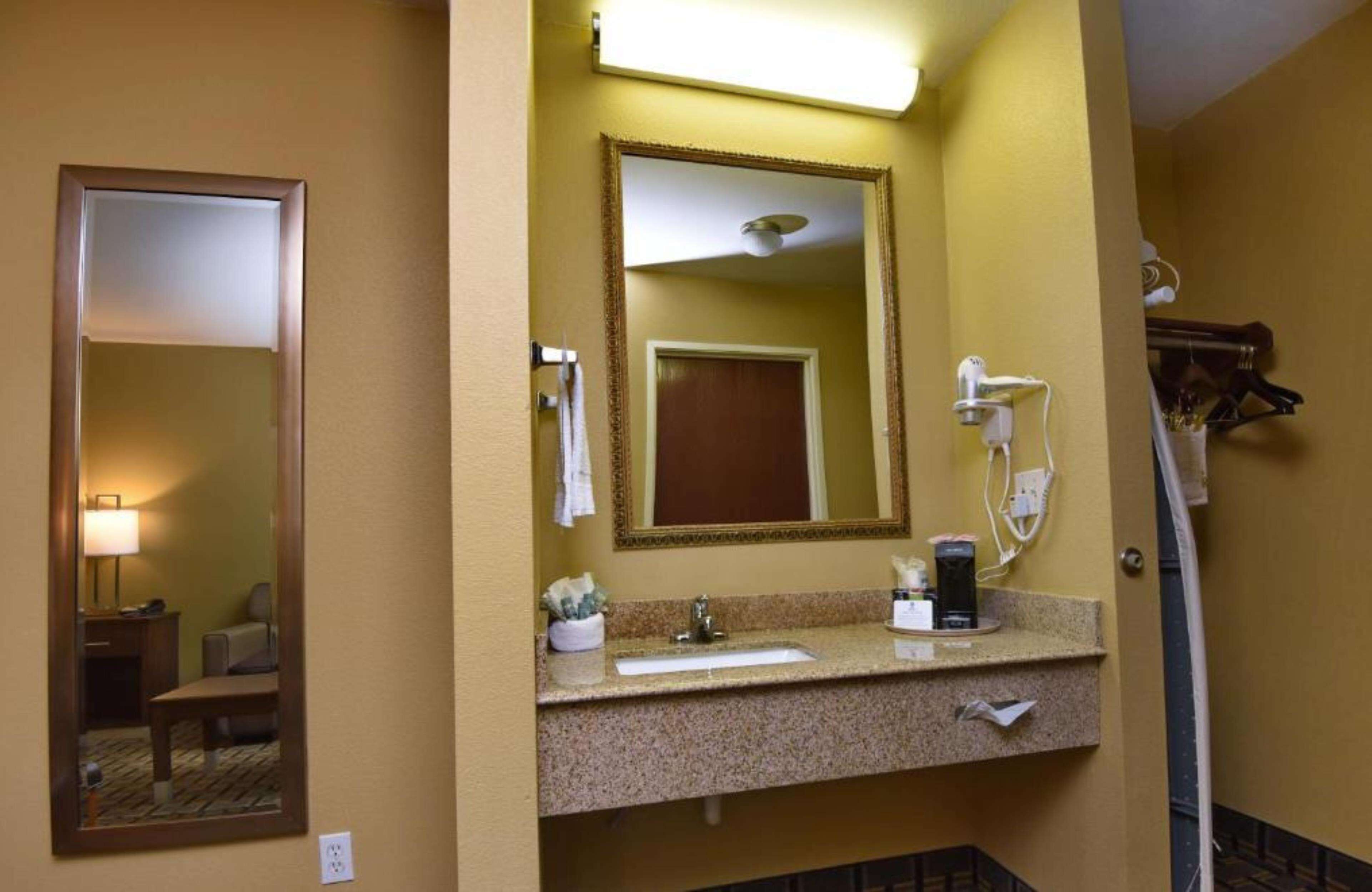 A hotel bathroom with a large mirror, a sink, and a shower area.