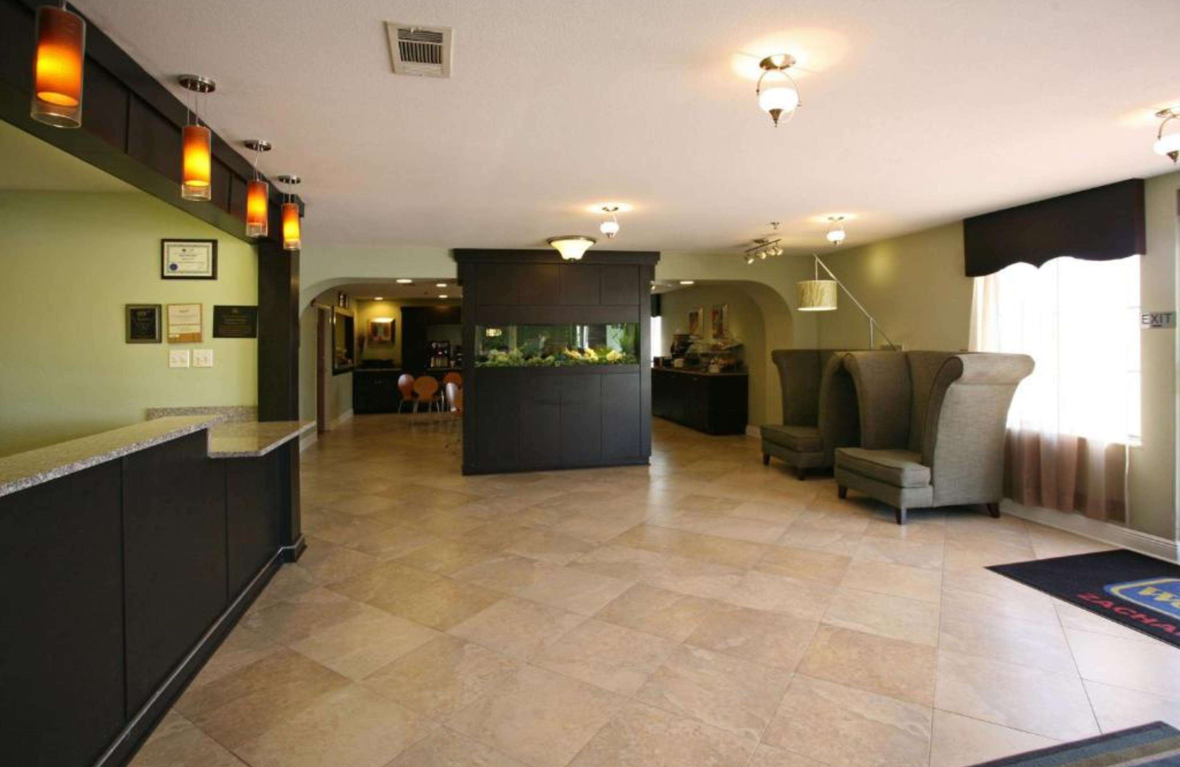 A spacious lobby with a reception desk, a fish tank, comfortable seating, and a large window.