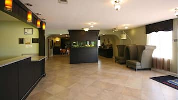 A spacious lobby with a reception desk, a fish tank, comfortable seating, and a large window.