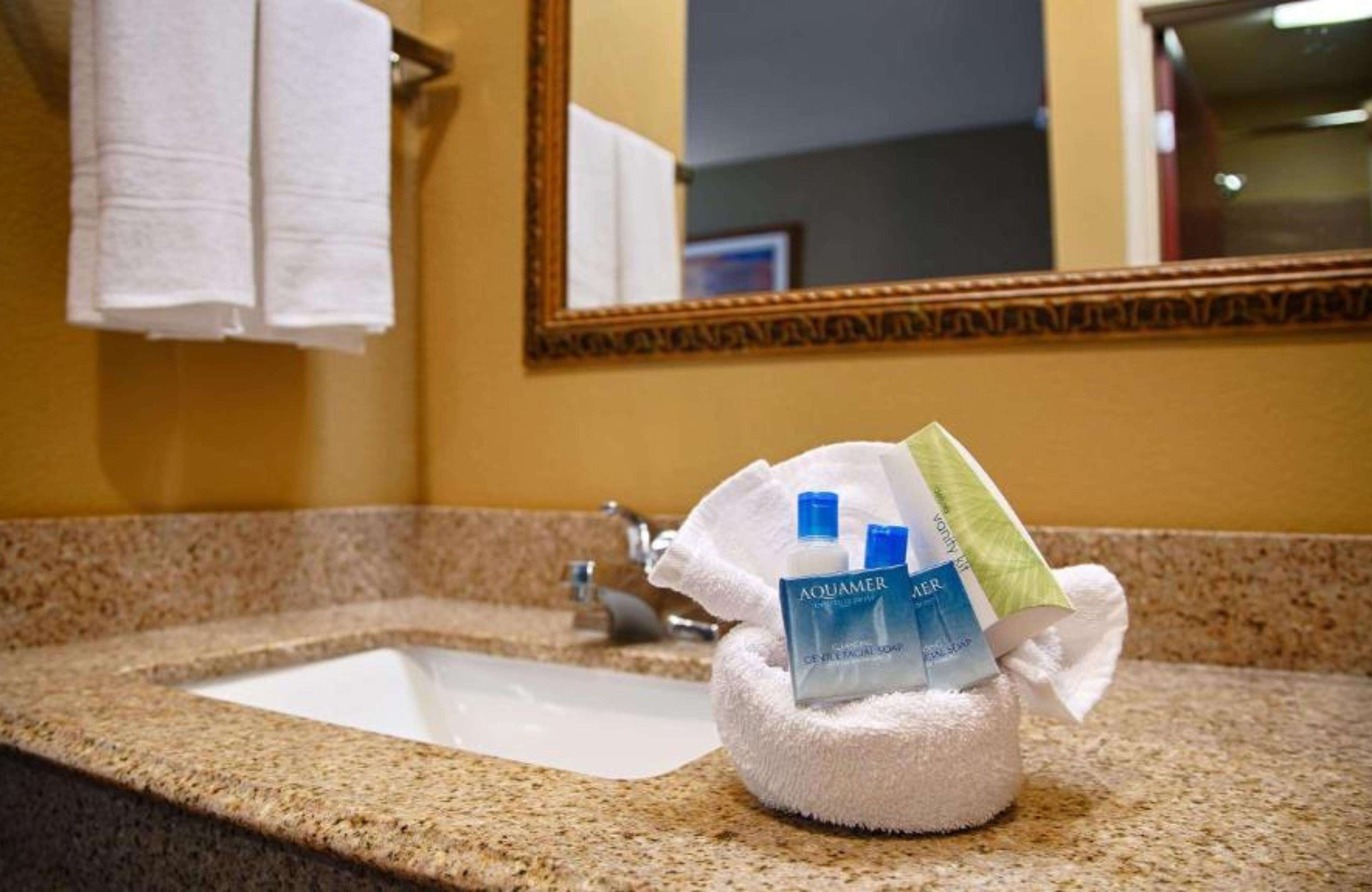 A bathroom sink with a towel dispenser holding toiletries.