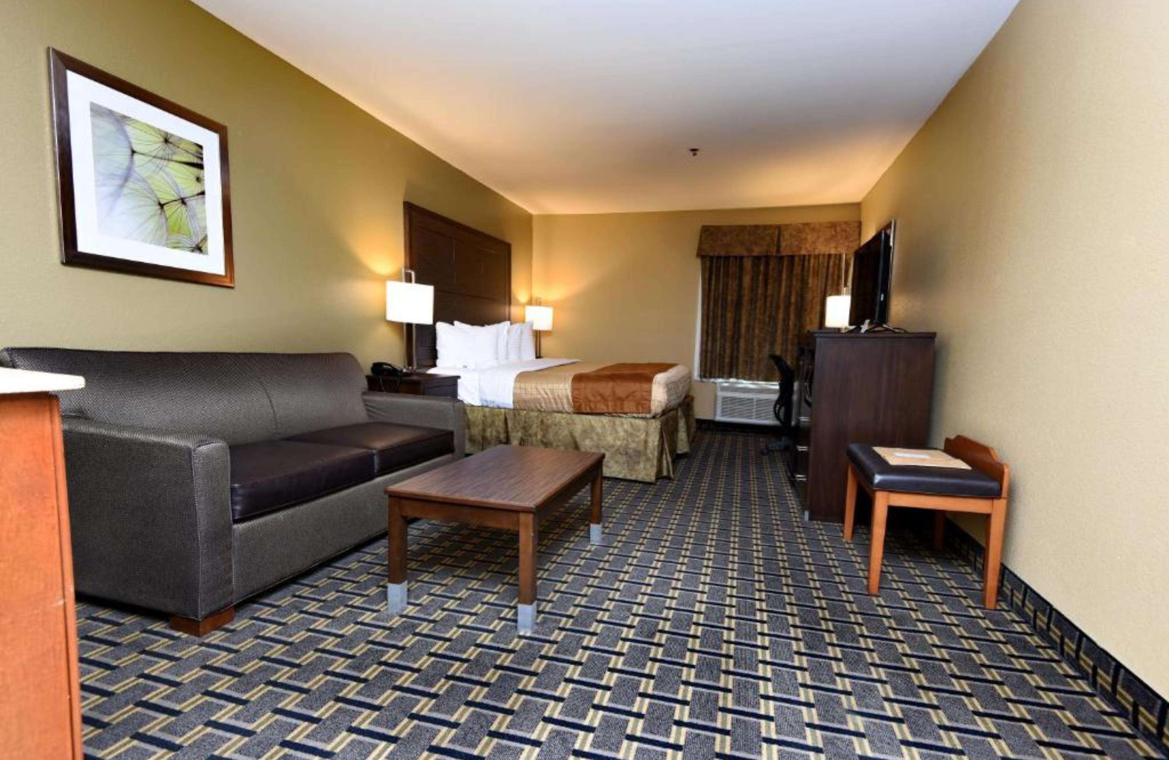 Une chambre d’hôtel avec un canapé, un lit, un bureau, une chaise et une moquette à motifs.