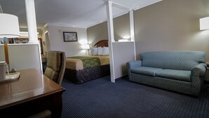 A hotel room with a bed, a sofa, a desk, and a lamp.