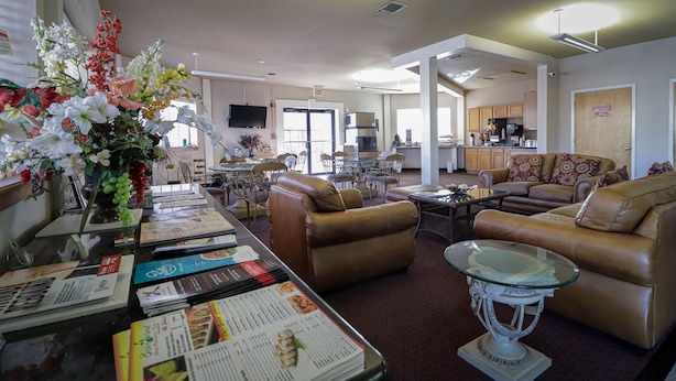 A spacious living room with leather sofas, a glass coffee table, and a dining area with a glass table and chairs.