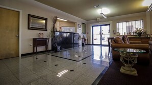 A spacious lobby with a tiled floor, a reception desk, a sofa, and a coffee table.