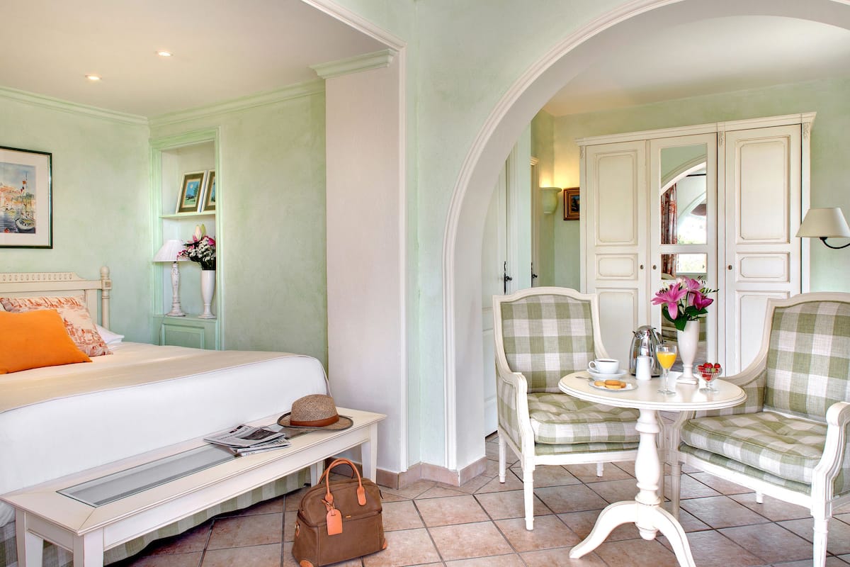 A bedroom with a bed, bedside table, and a chair with a table.