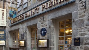 A stone building with a sign reading "AUDRIGUE SAINT PIERRE" and a hotel sign above the entrance. - Auberge Saint-Pierre (Le Mont-Saint-Michel)