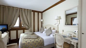 A hotel room with a bed, a desk, a chair, a television, and a window with curtains.
