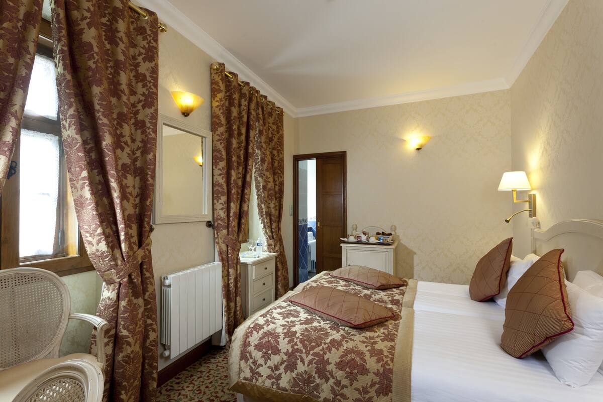 Een hotelkamer met een bed, een stoel, een dressoir en een spiegel.
