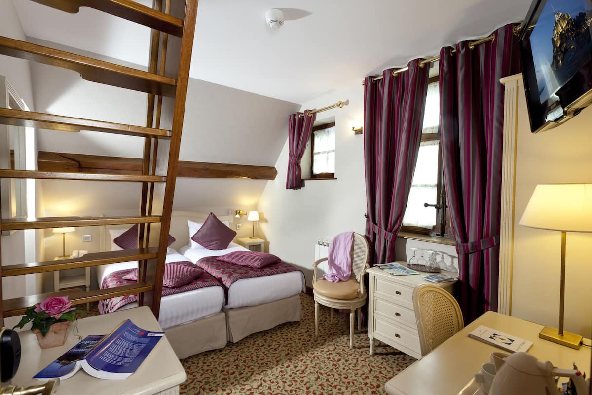 Een hotelkamer met een bed, nachtkastje, bureau, stoel en een raam met gordijnen.