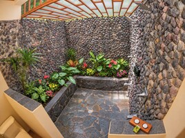 A stone-tiled indoor garden with a variety of plants and a small seating area.