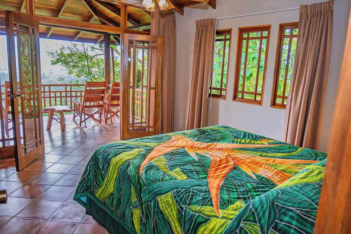 Une chambre avec un grand lit, des meubles en bois et une vue sur la verdure.
