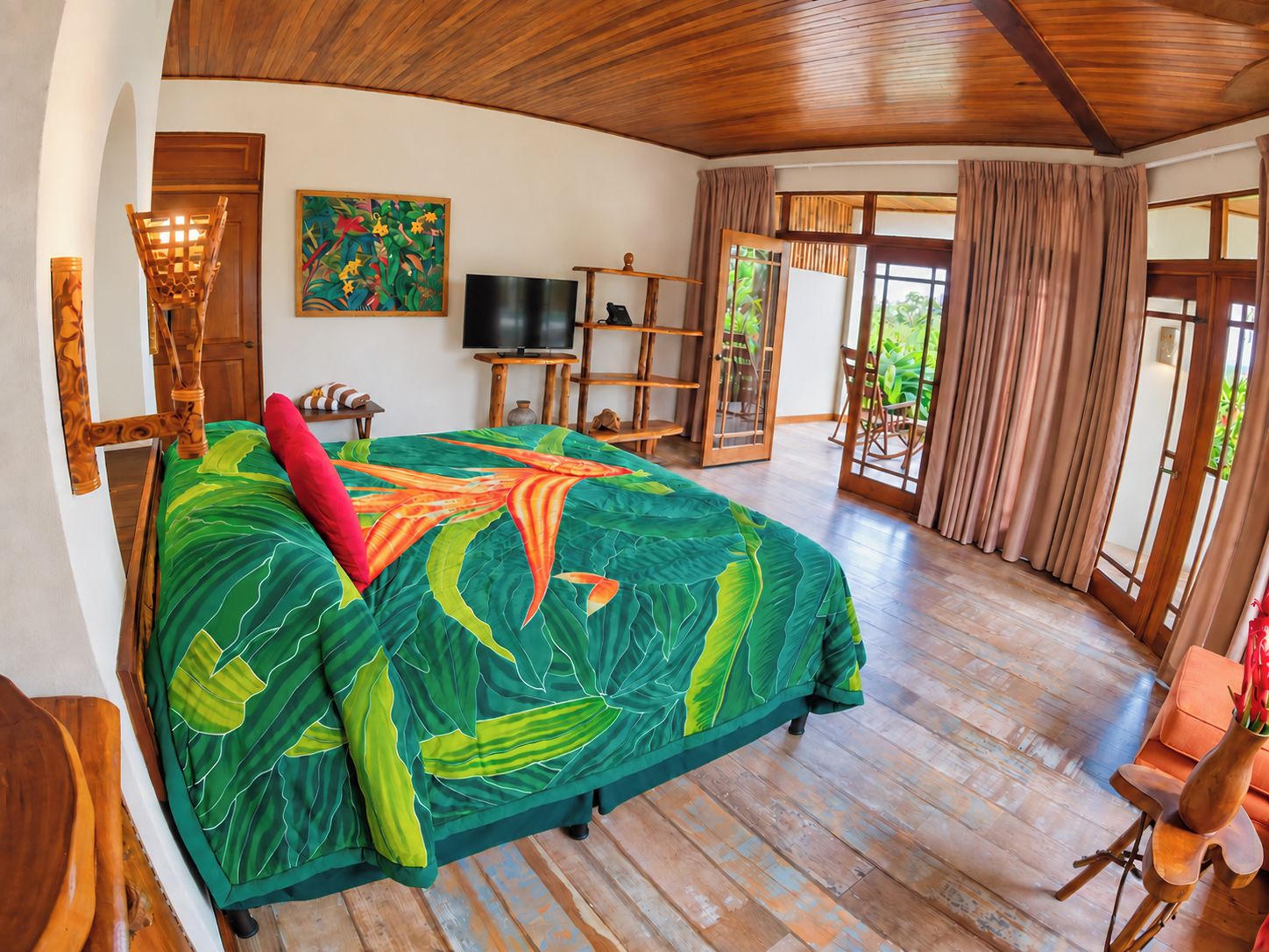 A spacious room with a large bed, a television, and a wooden ceiling.