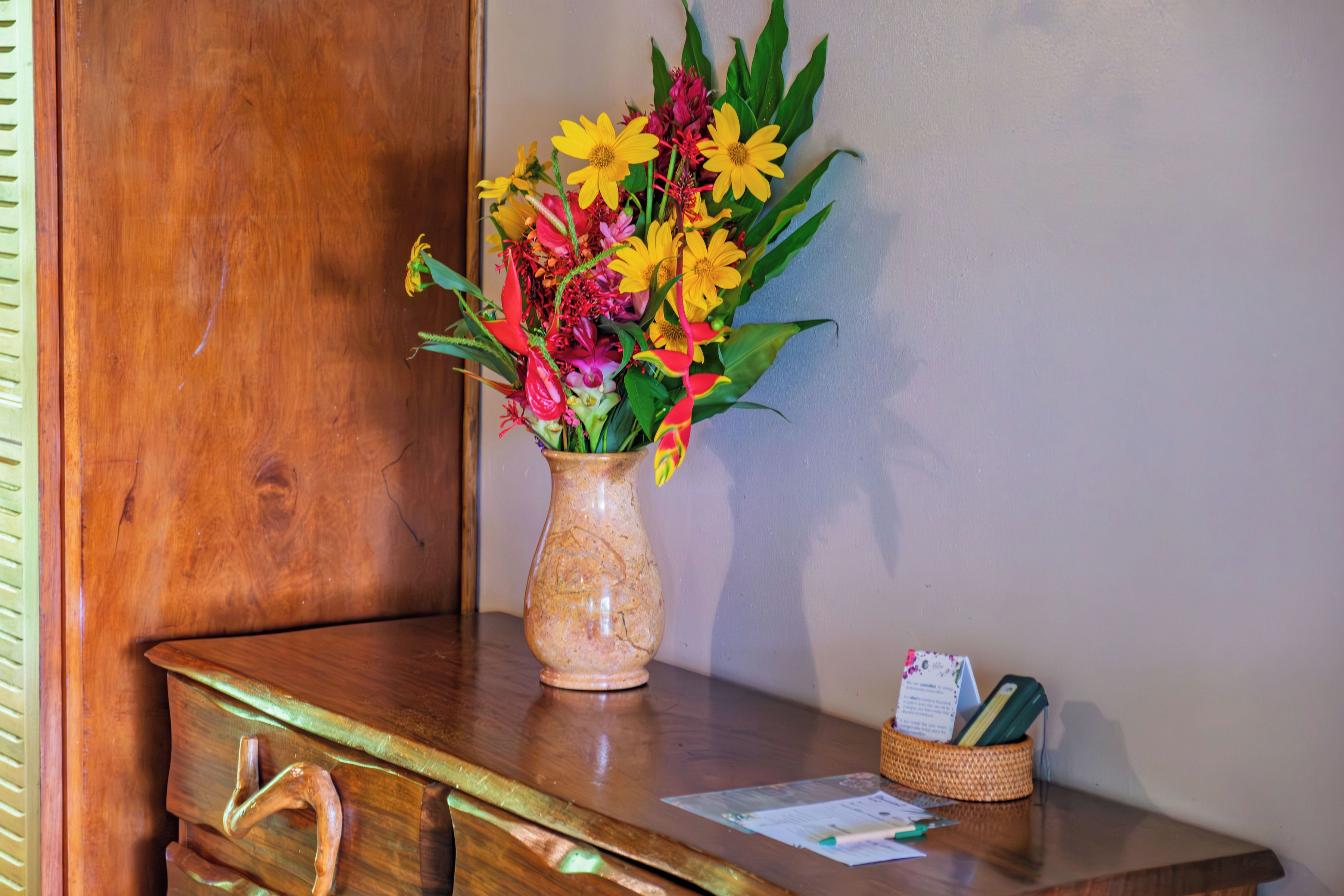 Un escritorio de madera con un florero, un cajón y una pequeña cesta con objetos.