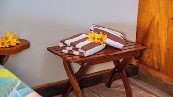 A small table with a cushioned bench against the wall, featuring neatly folded towels and a vase with flowers.