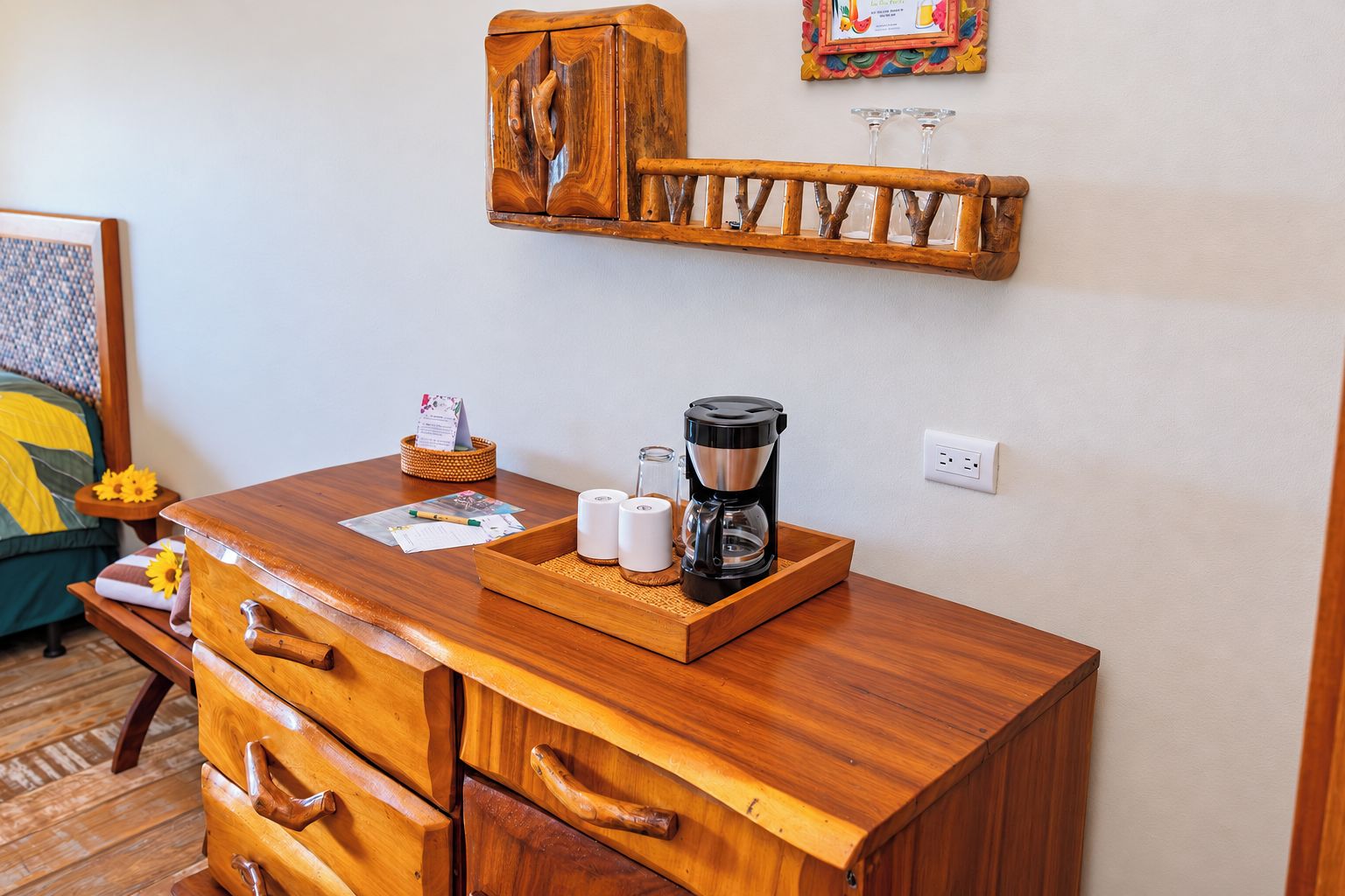 Un aparador de madera con cajones, una cafetera y una bandeja con tazas y una cesta.