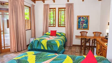 A bedroom with a bed, a desk, chairs, and a painting on the wall.