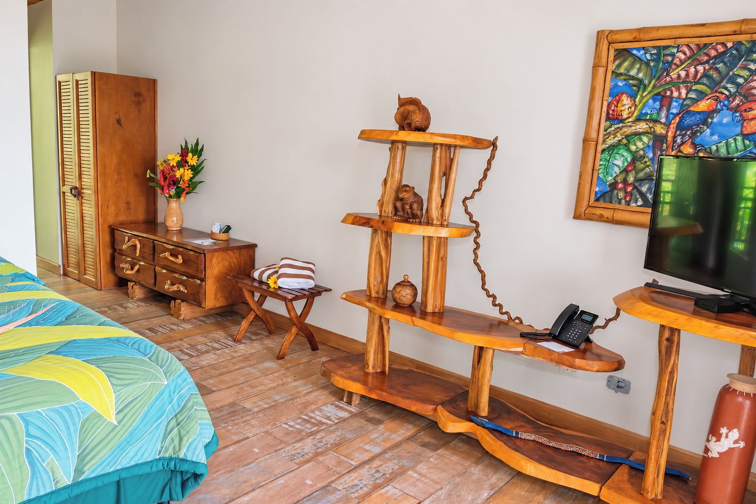 A bedroom with a bed, wooden furniture, a television, and a painting on the wall.