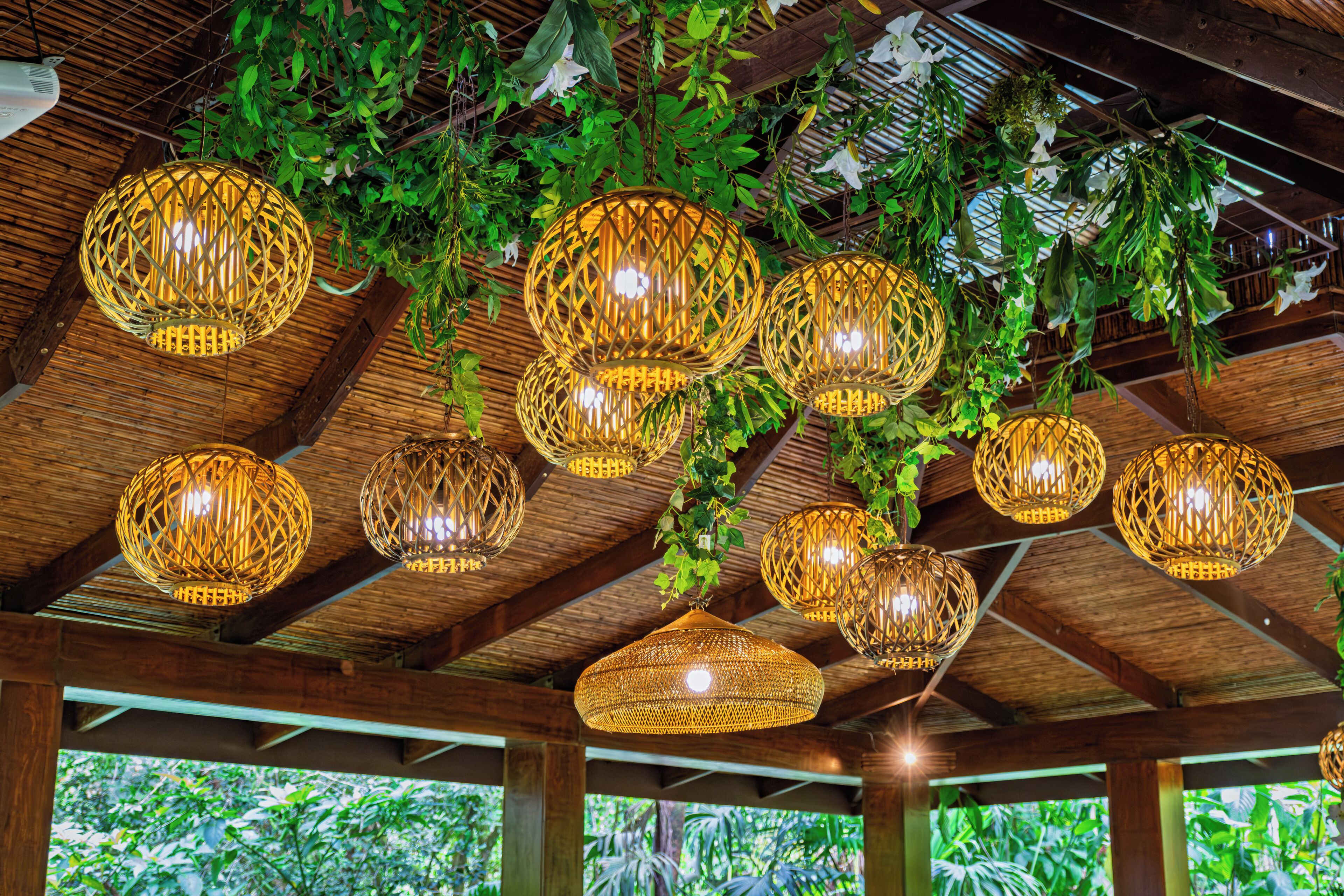 A ceiling with multiple woven light fixtures and hanging greenery.