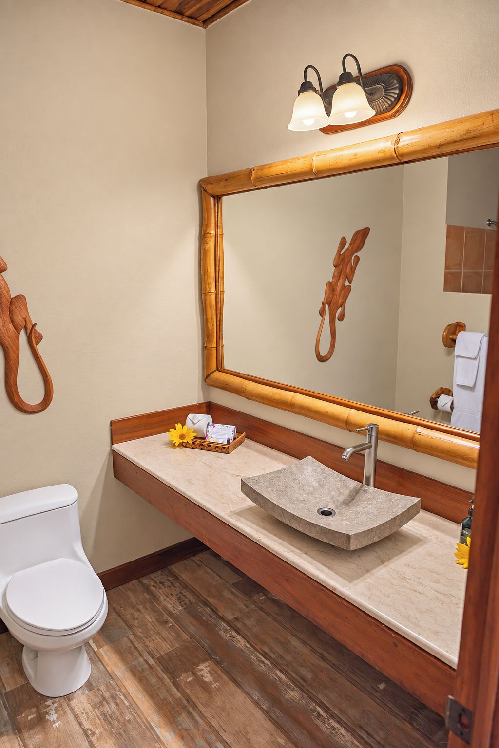 A bathroom with a wooden vanity, a large mirror, a white toilet, and a wooden floor.