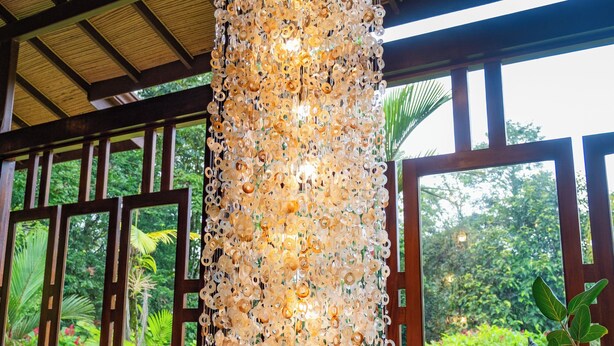 A room with a wooden floor, large windows, and a decorative light fixture made of circular objects. - Lost Iguana Resort and Spa (La Fortuna)