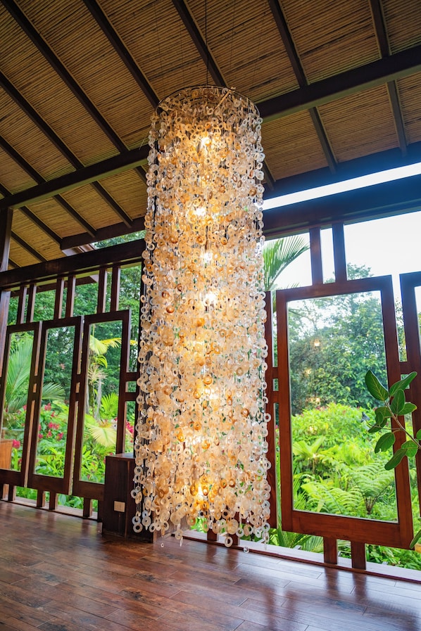 A room with a wooden floor, large windows, and a decorative light fixture made of circular objects.