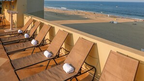 A beachside balcony with sun loungers and a view of the ocean. - Beach Quarters Resort (Virginia Beach)