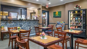 Un restaurante con mesas y sillas de madera, una barra de piedra y una máquina expendedora.