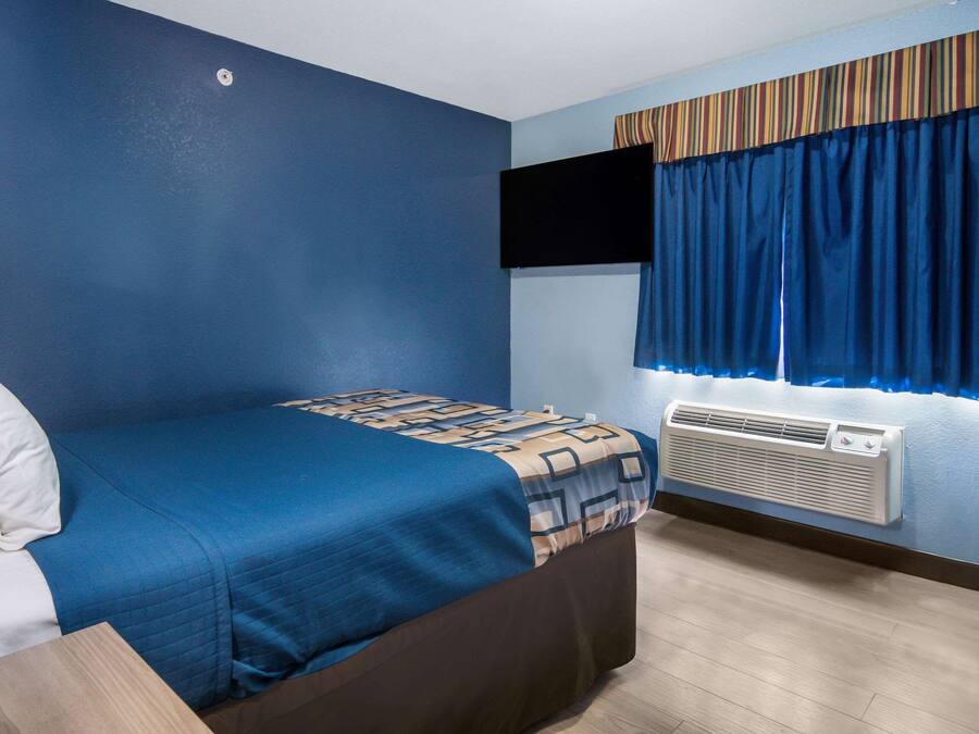 Un dormitorio con cama, televisor de pantalla plana en la pared y aire acondicionado.