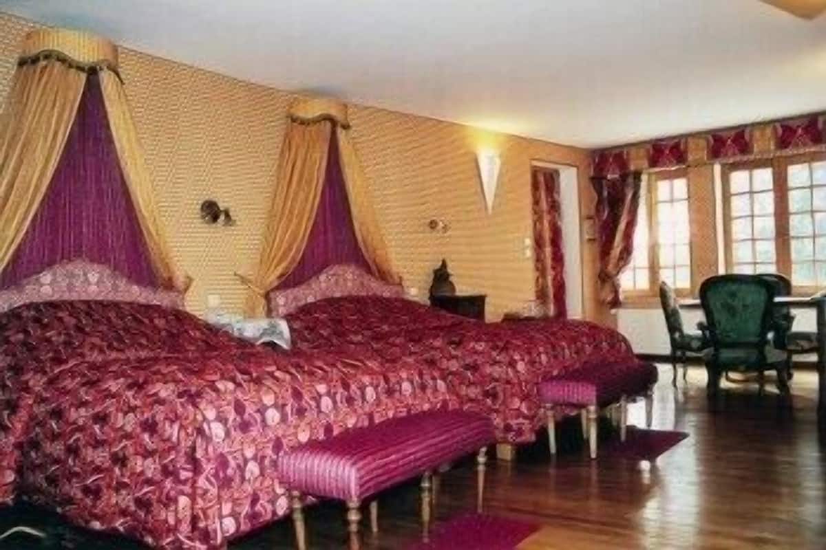 Ein Zimmer mit einem großen Bett, einem Sessel und einem Fenster.