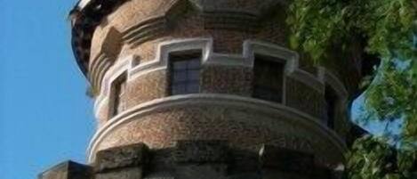 A stone tower with a conical roof, surrounded by greenery.