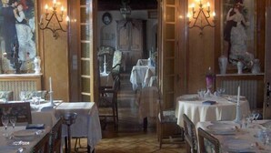 Un comedor con mesas dispuestas para una comida, paneles de madera y candelabros.