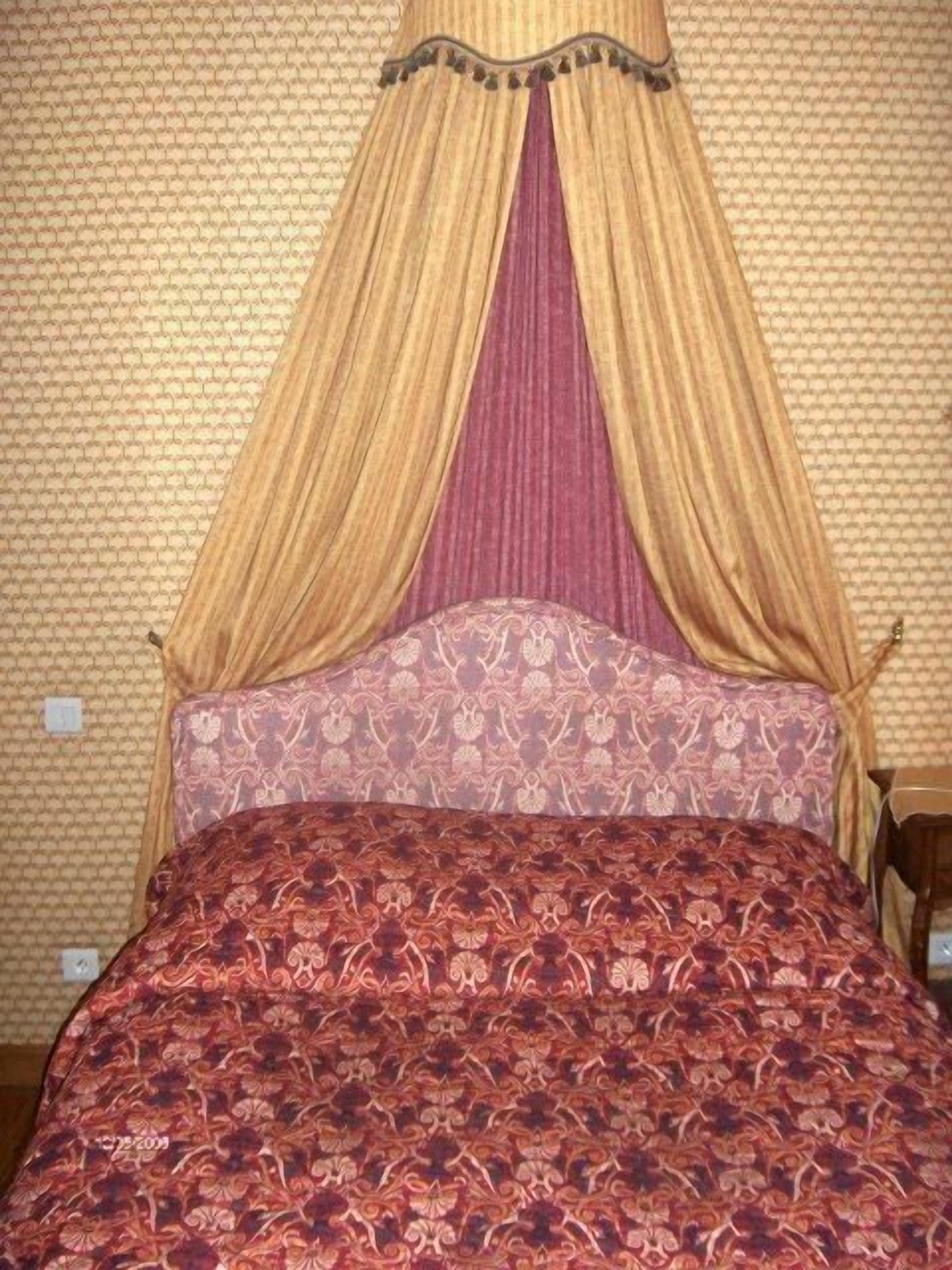 Ein Bett mit Baldachin und gemusterten Betttextilien.