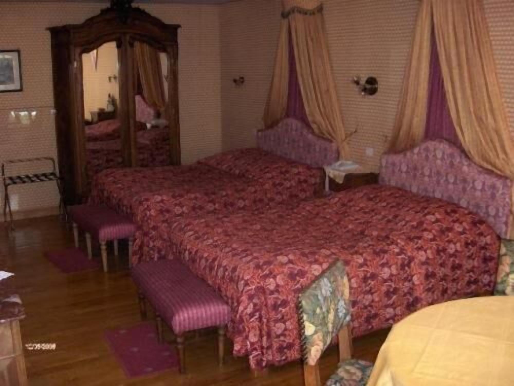 Un dormitorio con dos camas, un armario de madera, un banco y un espejo.