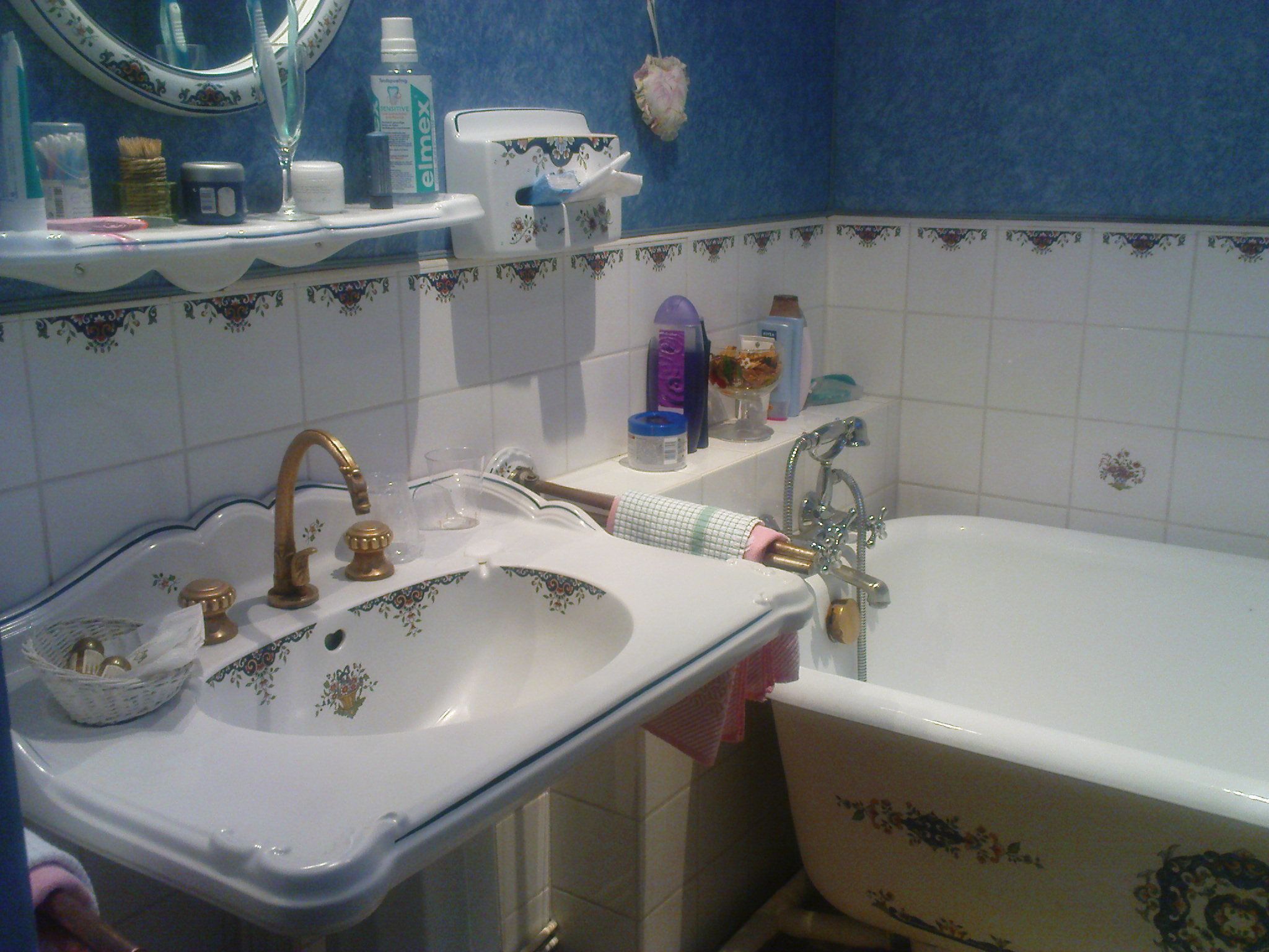 Un baño con lavamanos blanco, bañera y espejo.