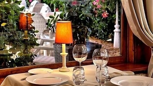 A table set for dining with plates, glasses, and a candle. - Hotel des Pins (Soulac-sur-Mer)