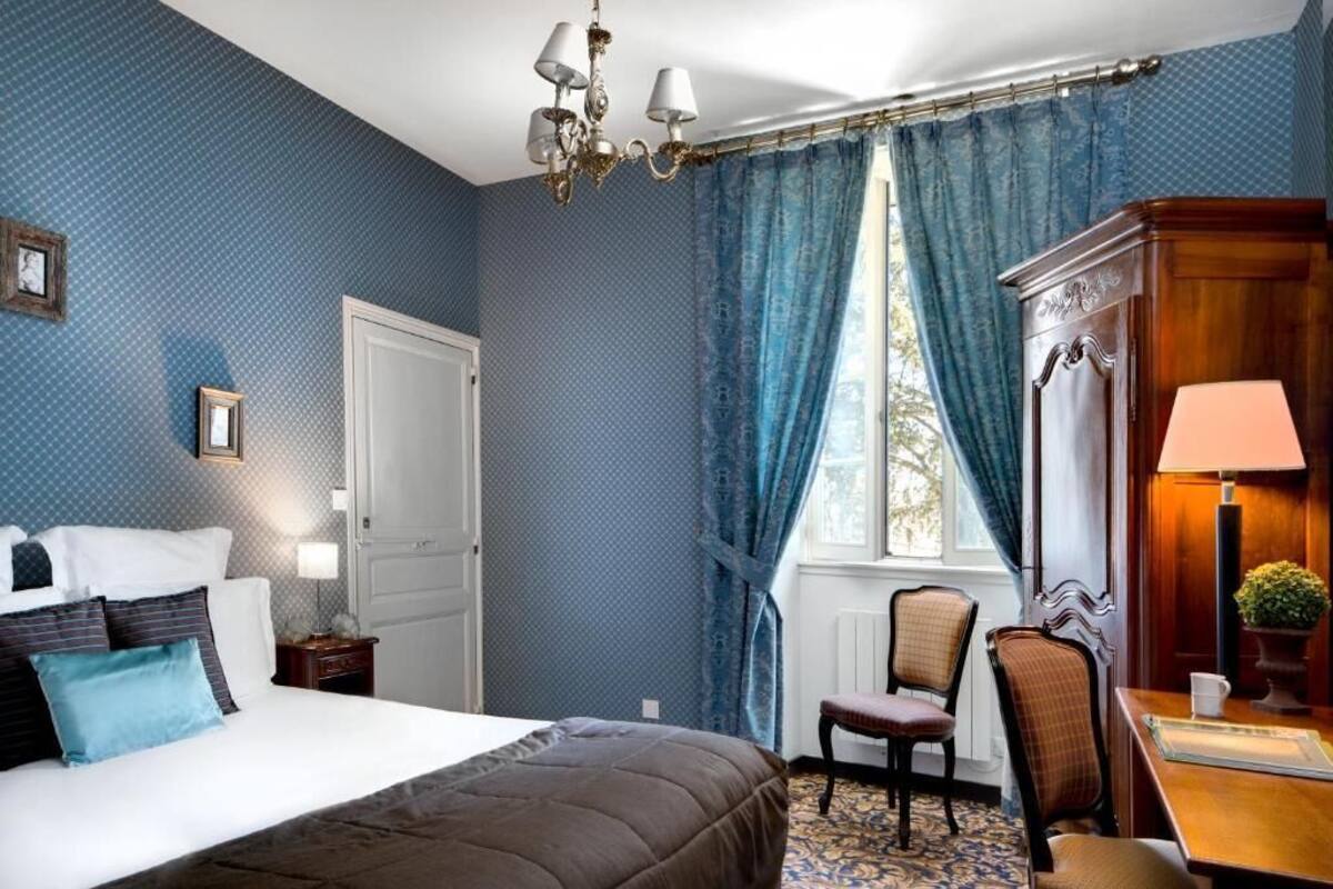 Une chambre à coucher avec un grand lit, un lustre, un bureau avec une lampe et une chaise.