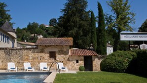 A stone building with a swimming pool, white lounge chairs, and a sign for 'Hôtel Saint-Martin'. - Hôtel Saint Martin - La Maison Younan (Saint-Maixent-l'Ecole)