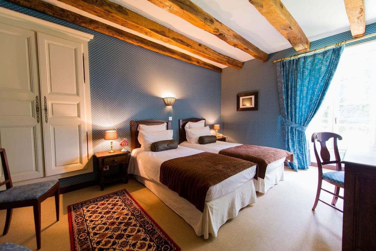 Une chambre d’hôtel avec deux lits, un plafond en bois, un tapis à motifs et une vue sur l’extérieur.