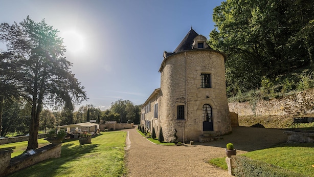 A stone building with a circular tower, surrounded by a gravel path and greenery. - Hôtel Saint Martin - La Maison Younan (Saint-Maixent-l'Ecole)