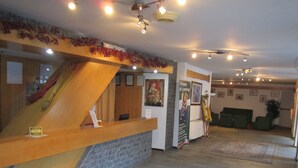 A hotel reception area with a wooden reception desk, a staircase, and a carpeted floor. - Hotel de la Telecabine (Courmayeur)