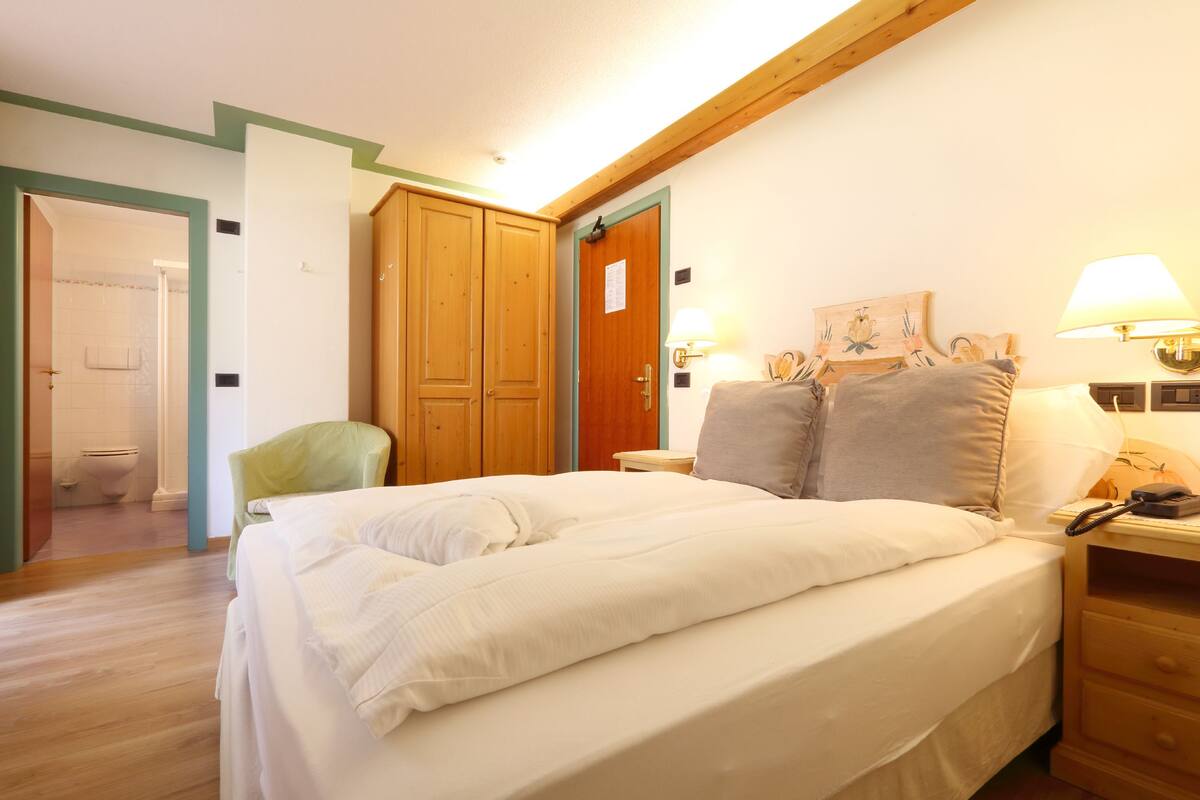 Un dormitorio con cama, mesitas de noche, una silla y un armario de madera.
