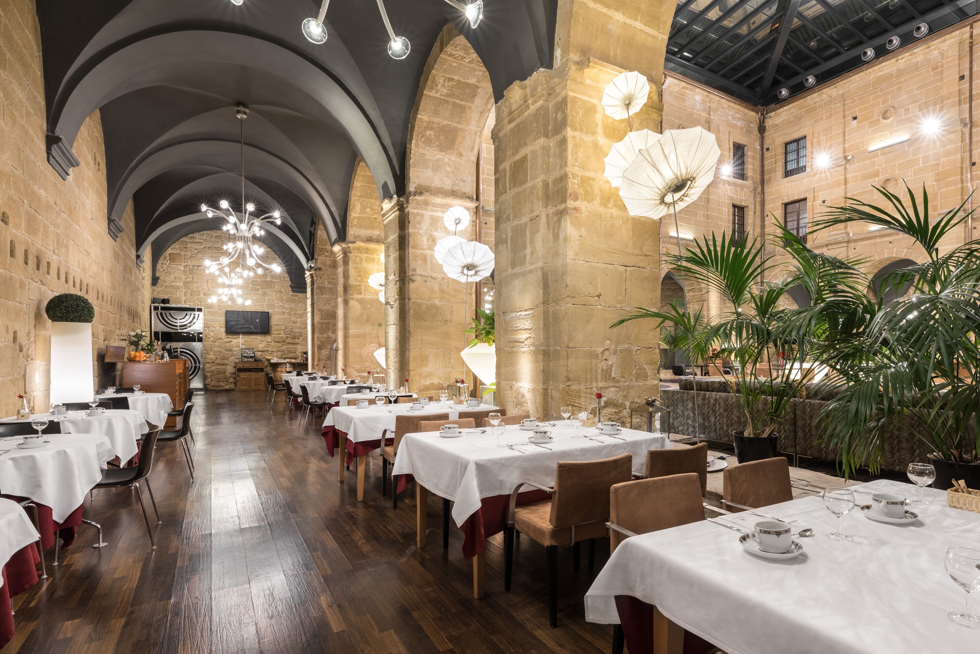A restaurant with high ceilings, arched stone walls, and tables set for dining.
