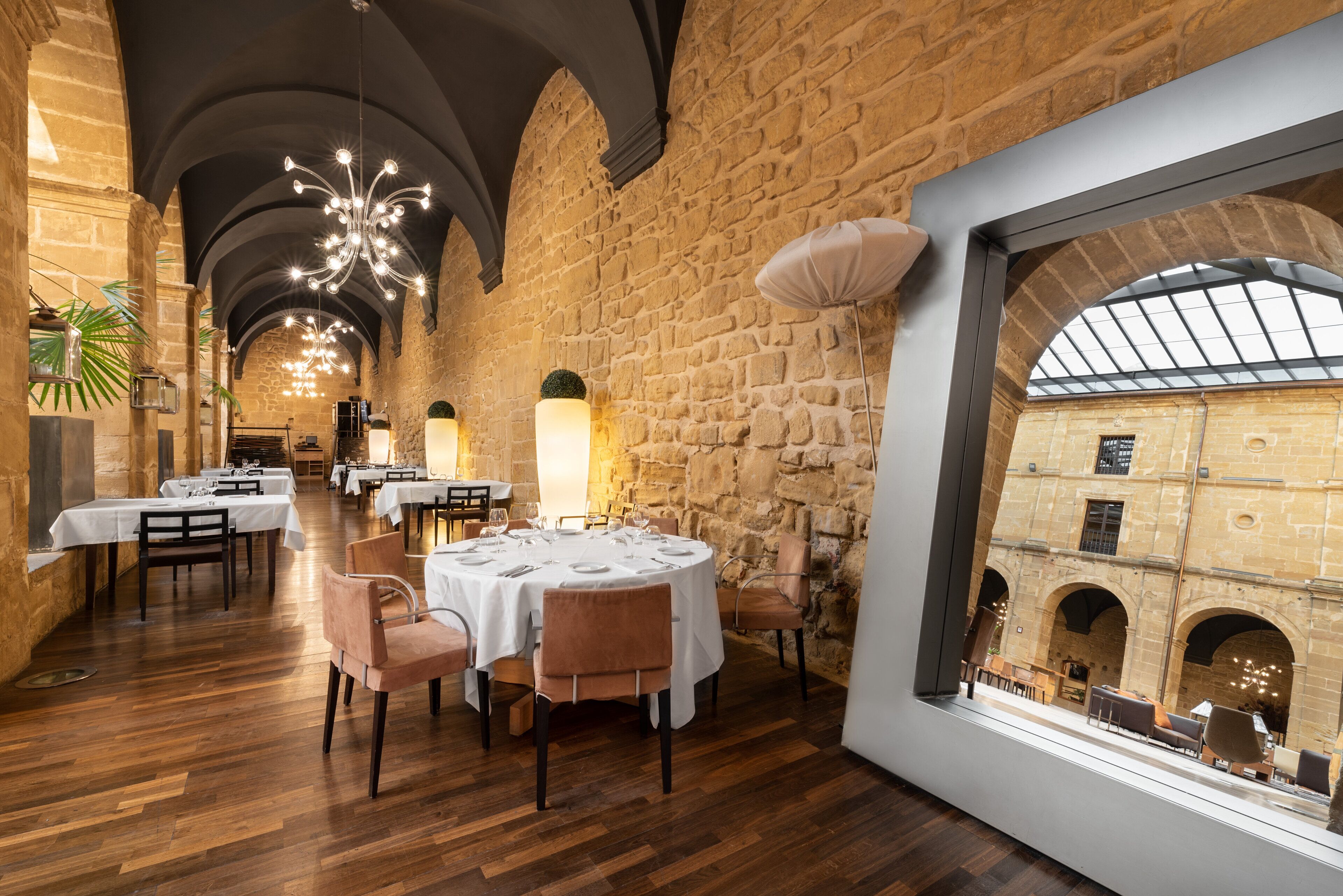 A restaurant with stone walls, wooden floors, and tables set for dining.
