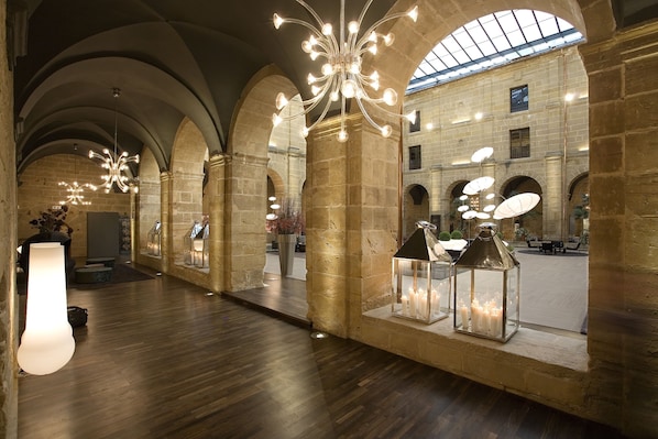 A spacious lobby with high arched ceilings, stone columns, and modern chandeliers.