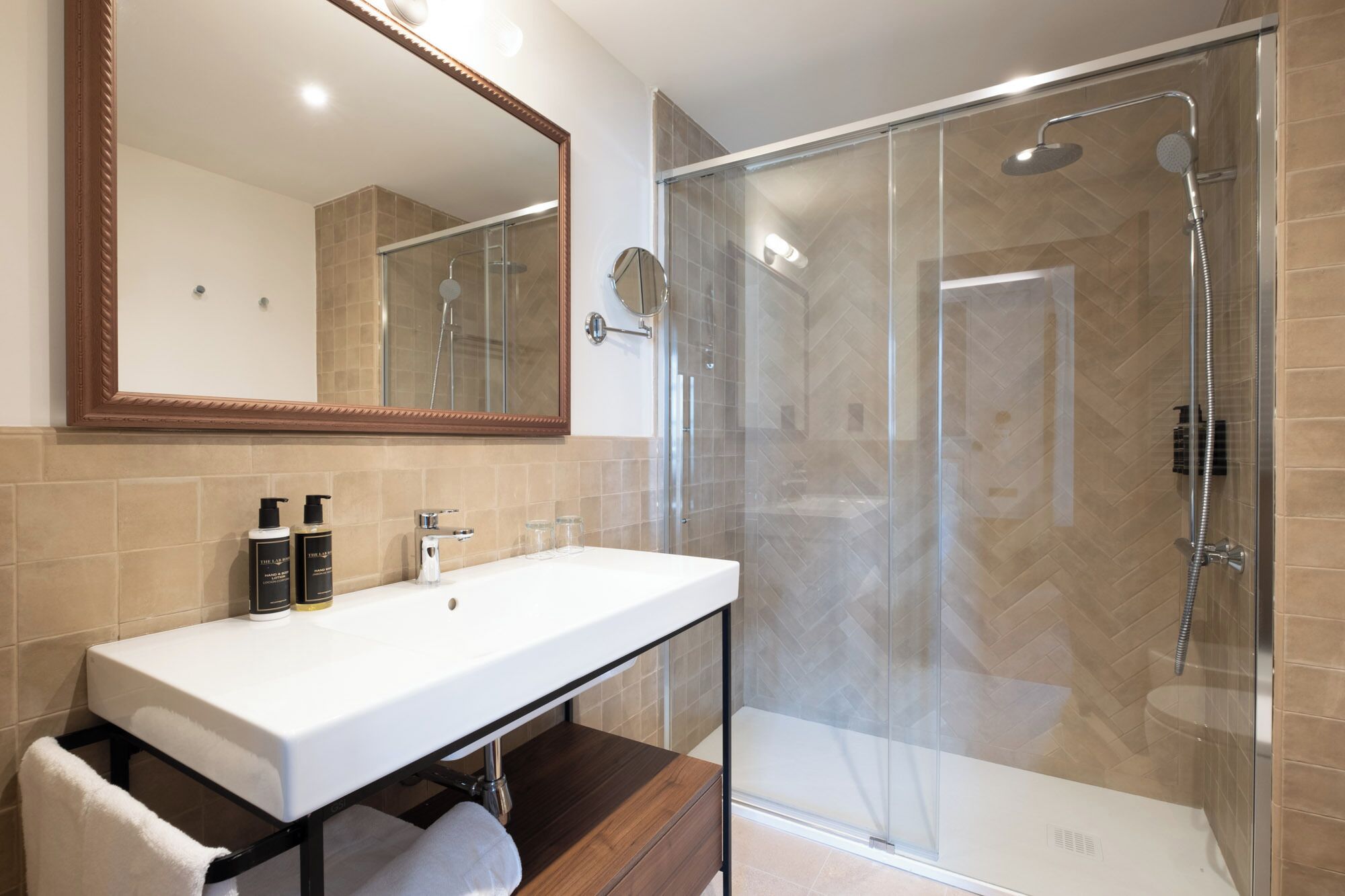 A modern bathroom with a glass-enclosed shower, a large mirror, and a white sink.